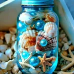 Dive into Calm with a Sea in a Bottle Sensory Bottle 5 A blue jar filled with sea shells, starfish, and blue pearls, surrounded by scattered shells.
