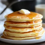 The Ultimate Guide to Fluffy Homemade Pancakes – Soft, Golden & Perfect Every Time 3 Tall stack of fluffy pancakes topped with melting butter and drizzled maple syrup
