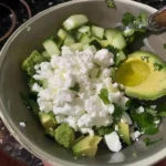 High Protein Cottage Cheese Avocado Salad 5 Bowl of diced cucumber, avocado, feta cheese, and half an avocado with olive oil