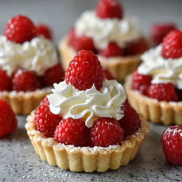 raspberry-tart-whipped-cream Mini raspberry tart topped with fresh raspberries and whipped cream