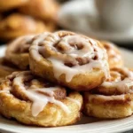 Freshly baked cinnamon roll cookies with icing drizzled on top.